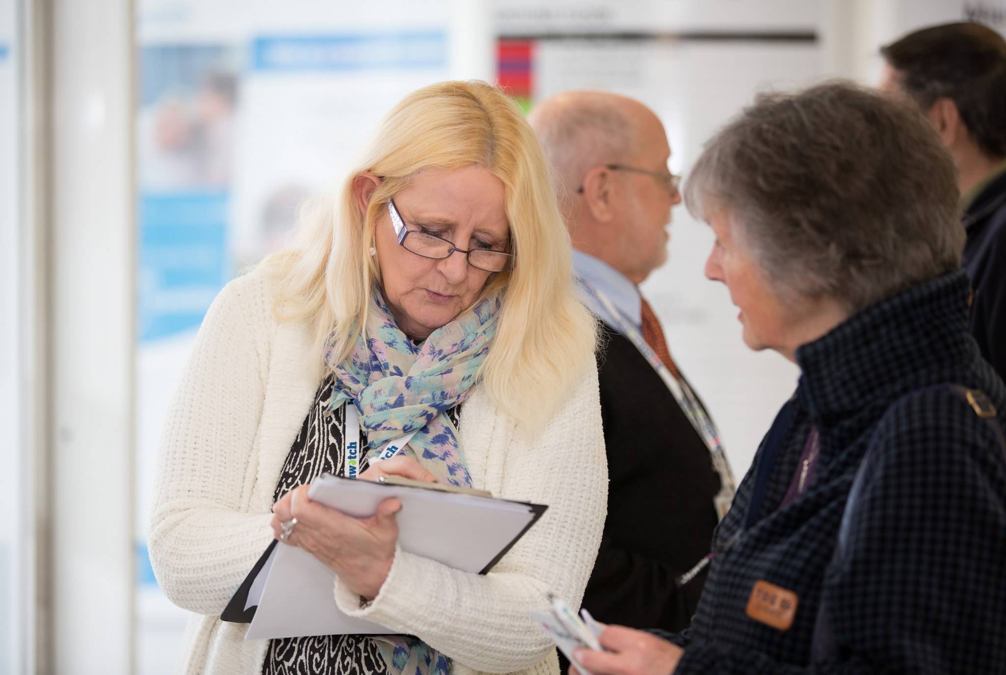 woman writing on a clipboard while talking to another woman