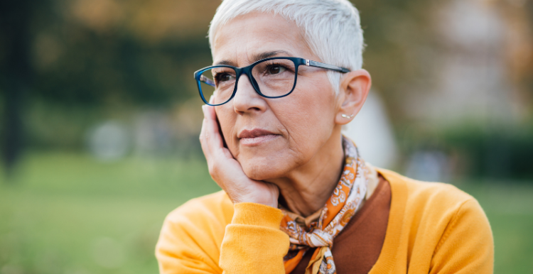 older woman with short cropped hair and glasses and wearing a yellow cardigan