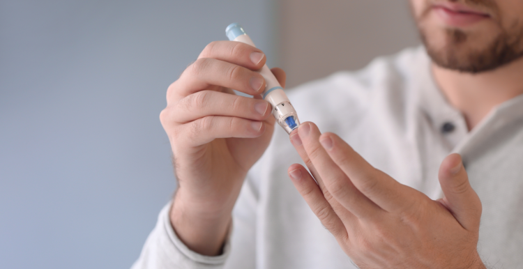 man using finger prick blood sugar test kit