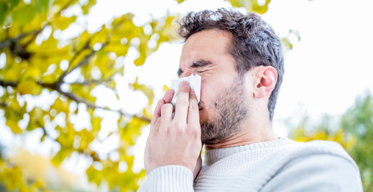 man holding tissue and sneezing 