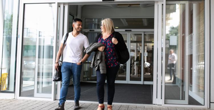 man and woman walking out of building