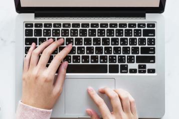 front cover of October-December 2022 quarterly report featuring hands on an open laptop keyboard