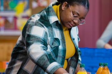 A woman organising bottles of orange squash on a table at a food bank.