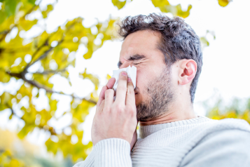 man holding tissue and sneezing 