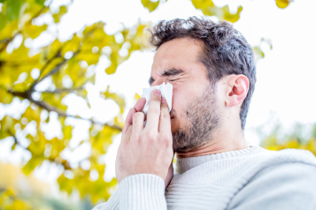 man holding tissue and sneezing