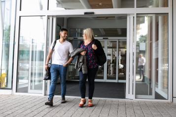 man and woman walking out of building