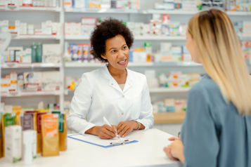 female pharmacist talks to female customer across a counter in a pharmacy