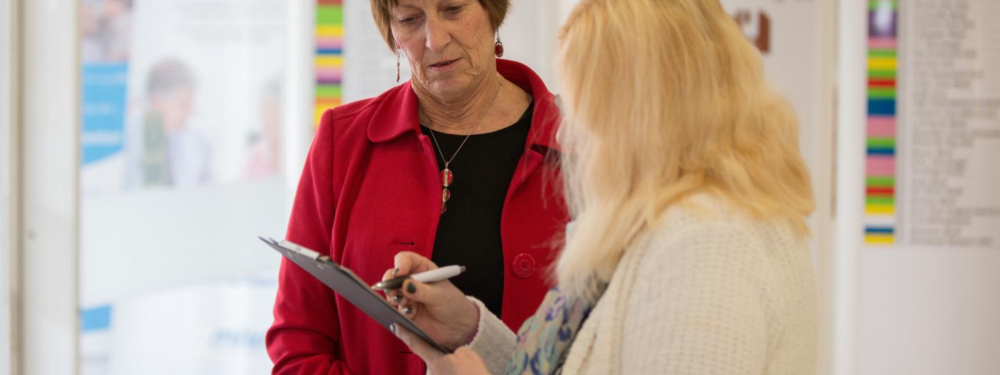 woman with clipboard talking to another woman