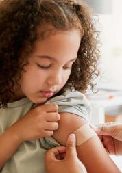 A young child having a small plaster placed on their upper arm.