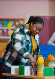 A woman organising bottles of orange squash on a table at a food bank.