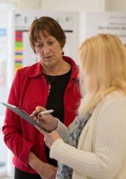 woman with clipboard talking to another woman